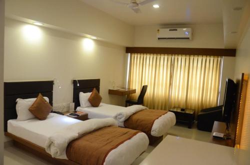 a hotel room with two beds and a television at Hotel Yuvraj in Vadodara