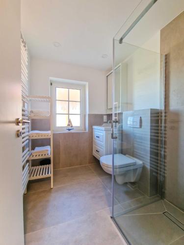 a bathroom with a toilet and a glass shower at Strandkrabbe in Greetsiel