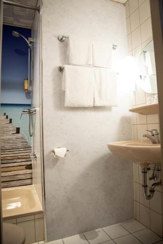 a bathroom with a shower and a sink and towels at Hotel Pfefferhöhe Alsfeld in Alsfeld