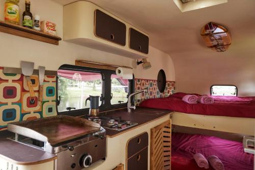 a kitchen with a stove and a bed in a caravan at Glampervan Julietta in Den Bosch