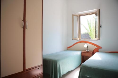 a small bedroom with two beds and a window at Villaggio Bellariva in Peschici