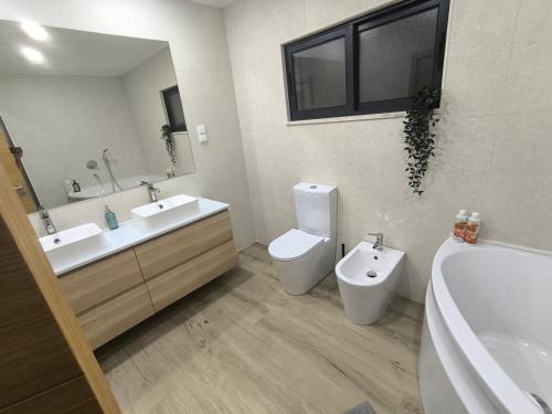 a bathroom with a tub and a toilet and a sink at Residência SB in Odivelas