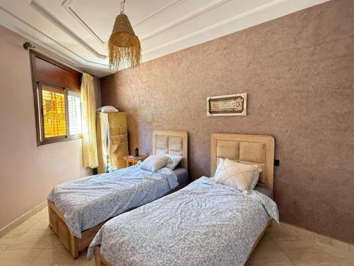 a bedroom with two beds and a chandelier at Saidia appart in Saïdia