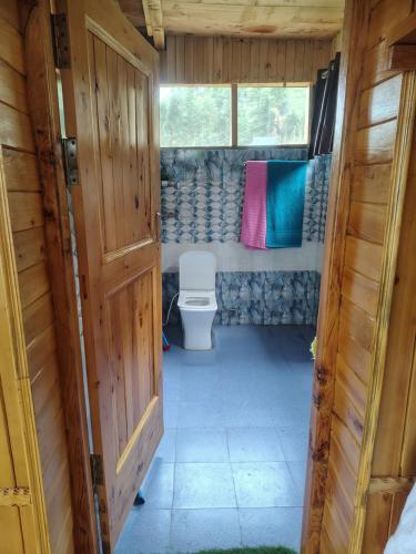 a bathroom with a toilet in a wooden house at Top Mountain Mist Near Jibhi in Banjār