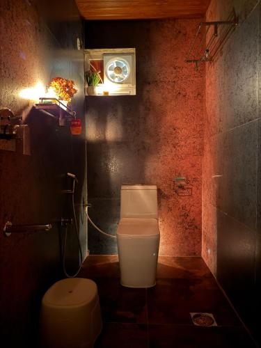 a bathroom with a toilet and a clock on the wall at Misty Garden Retreat in Nandigunda