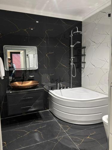 a black and white bathroom with a tub and a sink at Grand Teatro Hotel in Ganja
