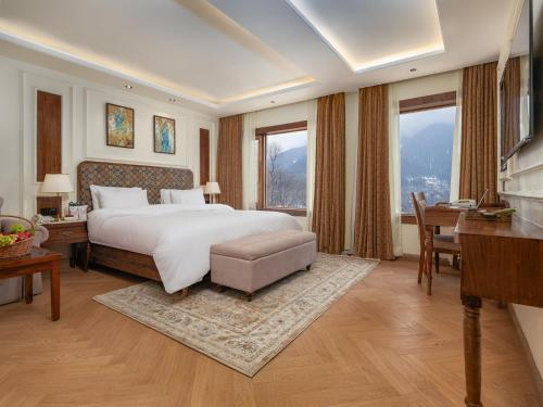 a bedroom with a large bed and a desk and a desk at The Harmukh Hills in Batakūt
