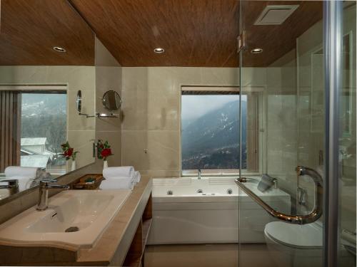 a bathroom with a tub and a sink and a toilet at The Harmukh Hills in Batakūt