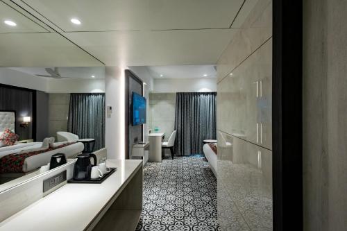 a hotel room with two beds and a bathroom at Sio Suites in Navi Mumbai