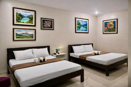 two beds in a room with pictures on the wall at Zolaria Hotel and Restaurant in Tagaytay