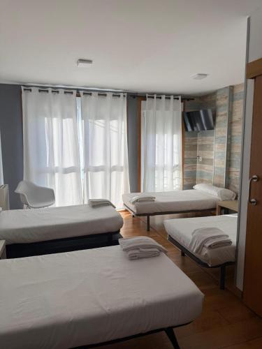 a room with four beds in a room at Albergue Alfonso II in Melide