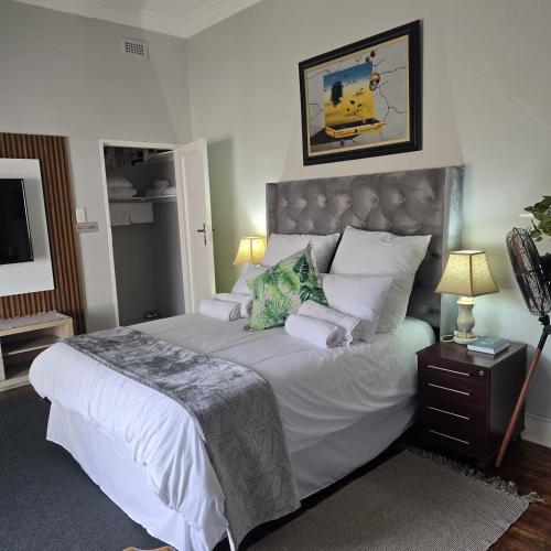 a bedroom with a large bed with white sheets and pillows at The Wentworth Guest House in Krugersdorp
