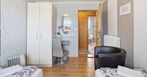 a room with two beds and a chair and a mirror at Guesthouse Kiljan in Blönduós