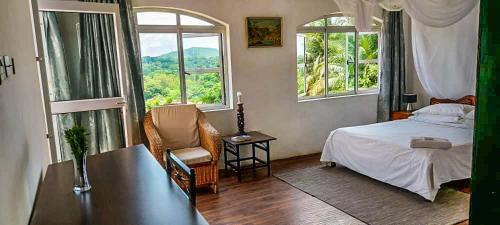 a bedroom with a bed and a chair and windows at Kabula Lodge in Blantyre