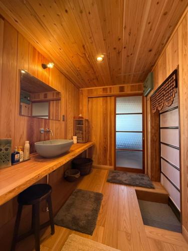a bathroom with a sink on a wooden wall at ゐらくさ in Yaizu
