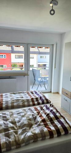 a bedroom with a bed and a balcony with a chair at Ferienwohnung Rütschlin in Nollingen