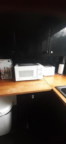 a microwave sitting on top of a wooden counter at Our Guests Are Royal (EL) Wellingborough in Wellingborough