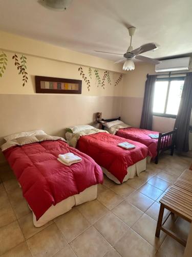 a bedroom with two beds with red sheets and a table at Hostal Tierra del Sol in Salta