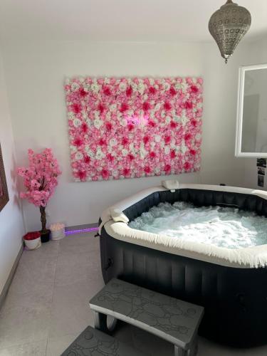 a bath tub in a room with a painting of roses at Suite Jacuzzi Giverny Paris in Freneuse