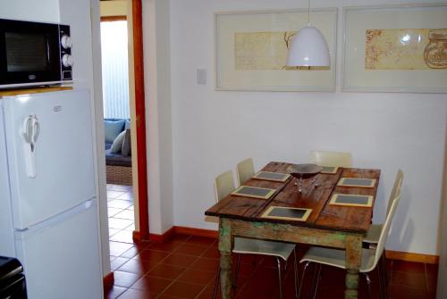 グラスコップにあるGraskop Harrie's Cottageのキッチン(木製テーブル、椅子、冷蔵庫付)