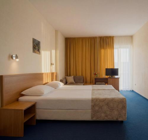 a hotel room with a large bed and a television at Hotel Perunika in Golden Sands