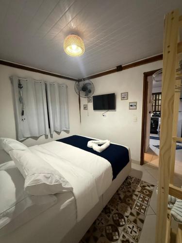 a bedroom with a large white bed and a television at Chalé com vista na vila centro histórico in Ilhabela