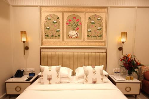 a hotel room with a bed and a picture on the wall at Dhiraj Dham in Nāthdwāra