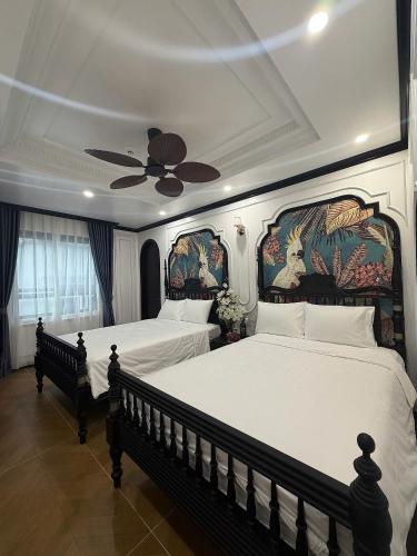 a bedroom with two beds and a ceiling fan at Indocharm Villa Cat Ba in Cat Ba