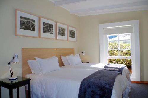Un dormitorio con una gran cama blanca y una ventana en Graskop Harrie's Cottage, en Graskop
