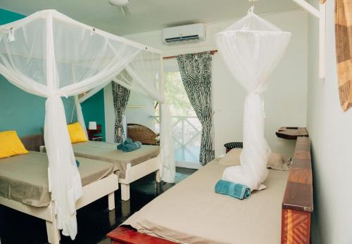 a bedroom with two beds with mosquito netting at Boa Gente Lodge in Vilanculos