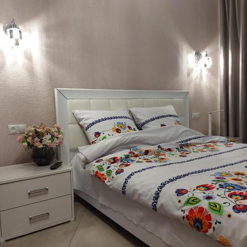 a bedroom with a white bed with flowers on it at Центр,дитяче містечко Казка in Mykolaiv