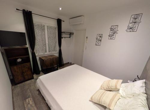 a bedroom with a white bed and a television at Chambre la Belle Étape in Martinet