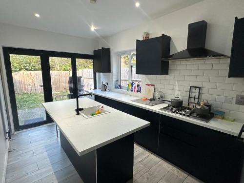 a kitchen with black cabinets and a white counter top at Massive cozy room with shared bathroom in Thornton Heath