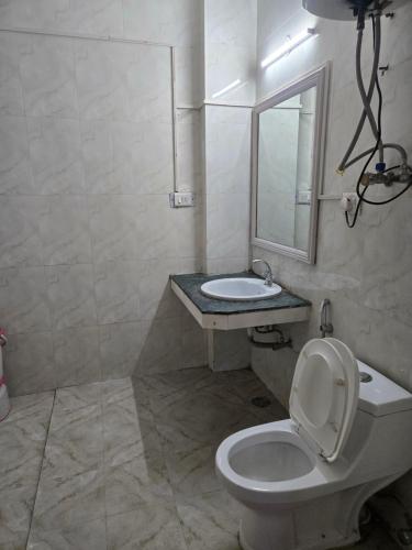 a bathroom with a toilet and a sink and a mirror at Kalinga Intercontinental By Maa Vaishno Hotels India Pvt Ltd in Manāli