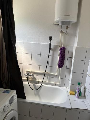 a white tiled bathroom with a sink and a blow dryer at Sweet home Jagodina in Jagodina