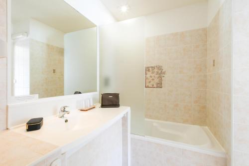 a white bathroom with a sink and a bath tub at Logis Hôtel La Forestière in Biscarrosse-Plage