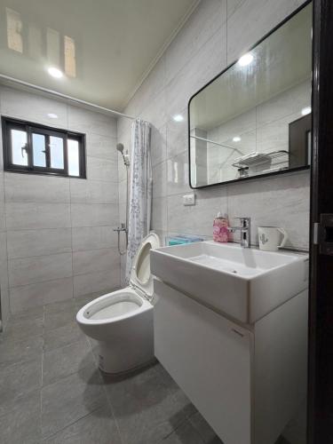 a bathroom with a toilet and a sink and a mirror at Siwei B&B in Hou-k'u-t'an