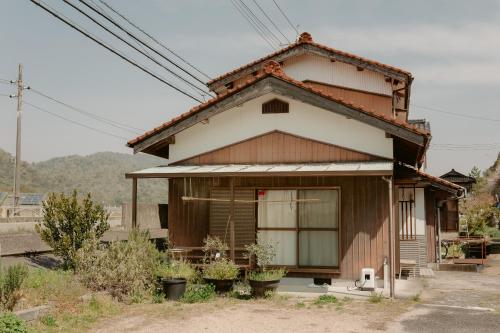 a small house with two potted plants in front of it at キッチンが使いやすい田舎の一棟貸 小さなお子様連れにおすすめ in Yamaguchi