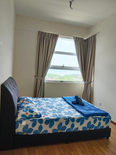 a bedroom with a bed with a blue blanket and a window at Seaview Emerald Sandakan in Sandakan