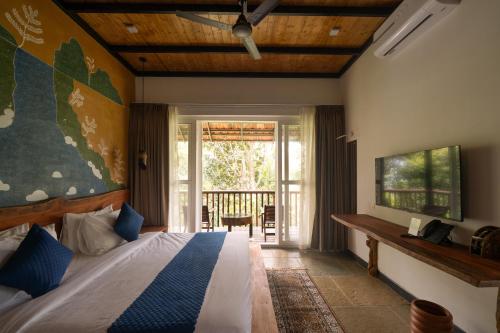 a bedroom with a bed and a sliding glass door at Aalterra Resort by The Almanac in Wayanad