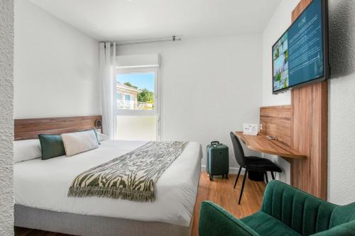 a hotel room with a bed and a desk and a computer at Logis Hôtel La Forestière in Biscarrosse-Plage