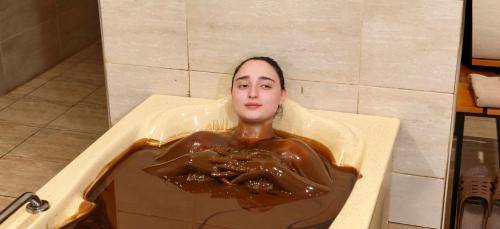 a woman in a bath tub covered in chocolate at Naftalan Central Wellness Resort in Naftalan