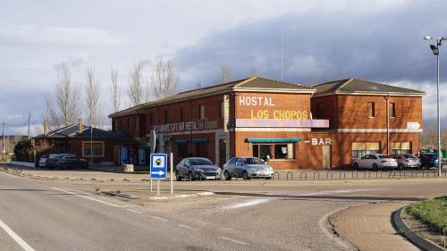 a large brick building with cars parked in a parking lot at Hostal Los Chopos in Osorno