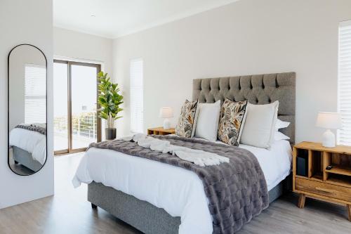 a bedroom with a large bed and a mirror at Salt & Feather in Yzerfontein