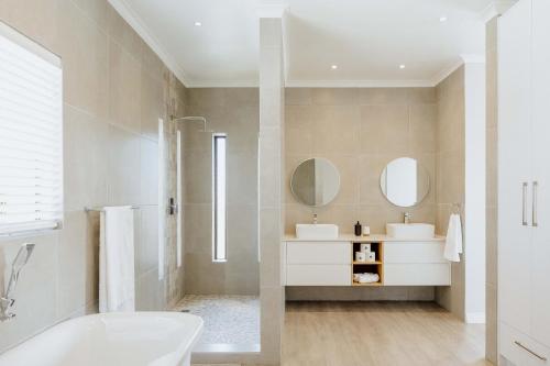 a bathroom with two sinks and a tub and mirror at Salt & Feather in Yzerfontein