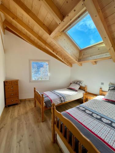 two beds in a room with a large window at Chalet Douce Noire in Brides-les-Bains