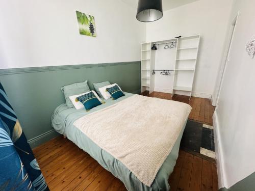 a bedroom with a large bed with blue pillows at Logement Océan in Boulogne-sur-Mer