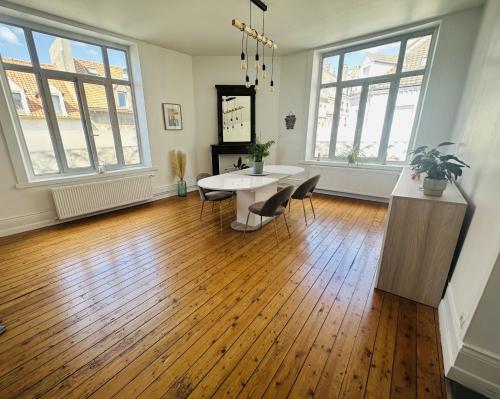 a living room with a table and chairs and windows at Logement Océan in Boulogne-sur-Mer