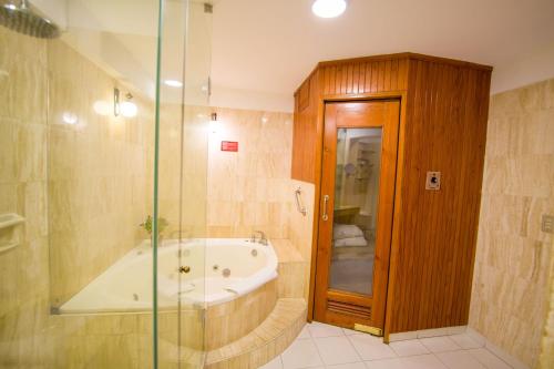 a bathroom with a tub and a glass shower at Hotel Britania San Borja in Lima