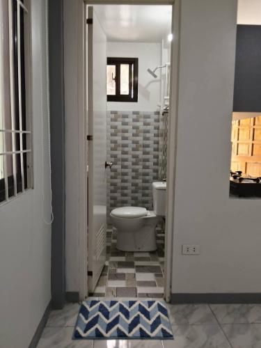 a bathroom with a toilet and a blue rug at Candava's Residence in Puerto Galera